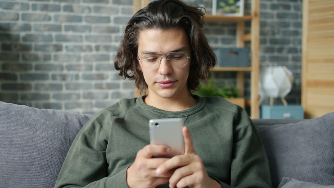 Iemand op de bank met een smartphone in de hand, IPTV kopen bij Hakuna TV